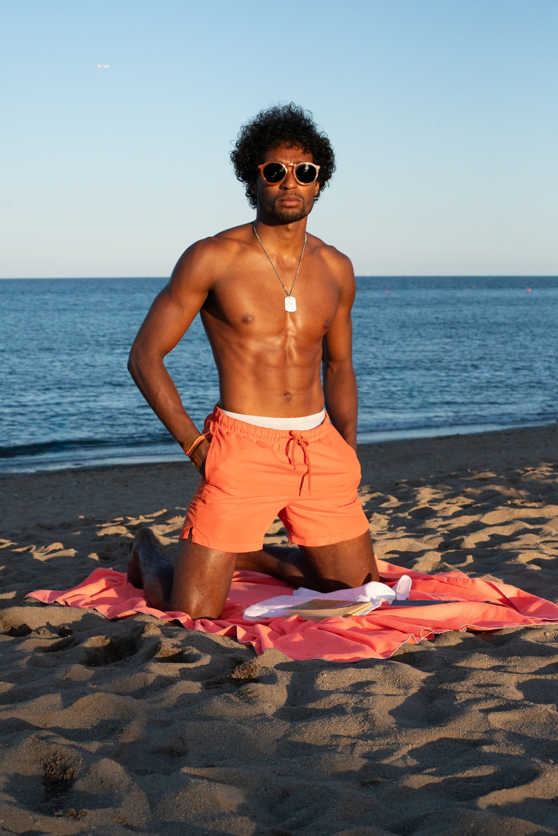 Muscular Brazilian Male Model Posing on Beach with Orange Swimwear and Sunglasses